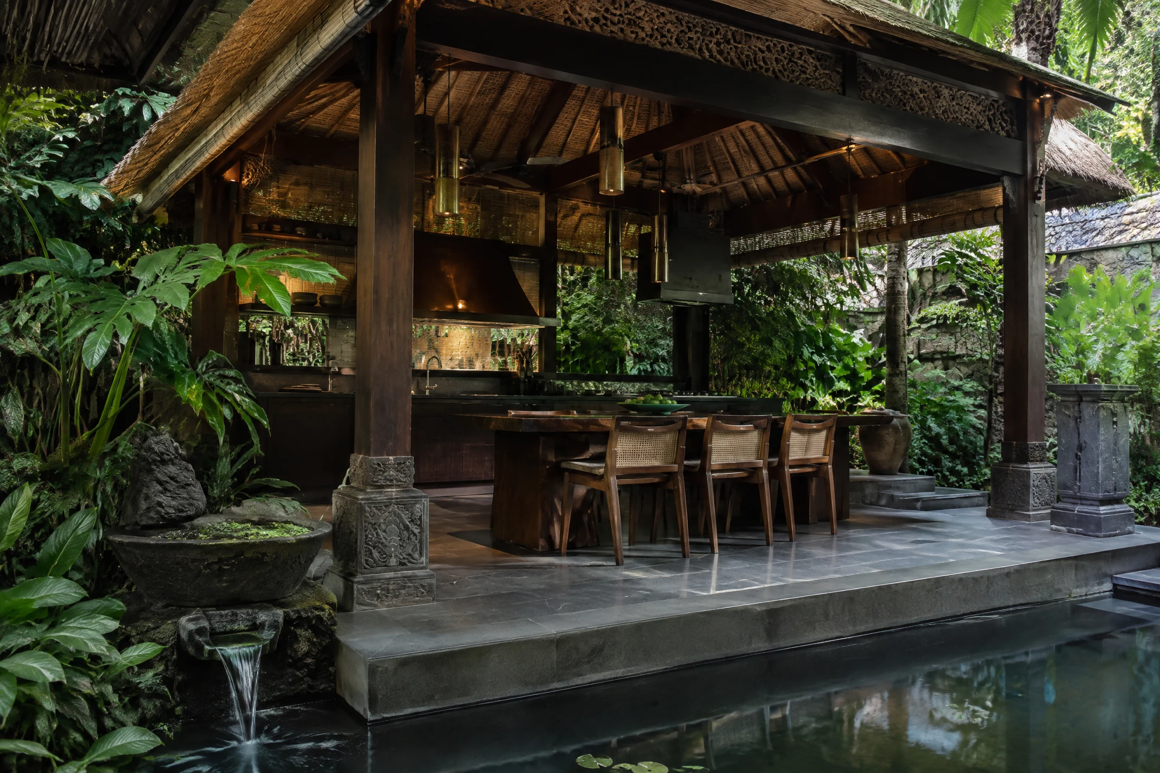 Bali-style outdoor kitchen pavilion with carved stone and a water feature