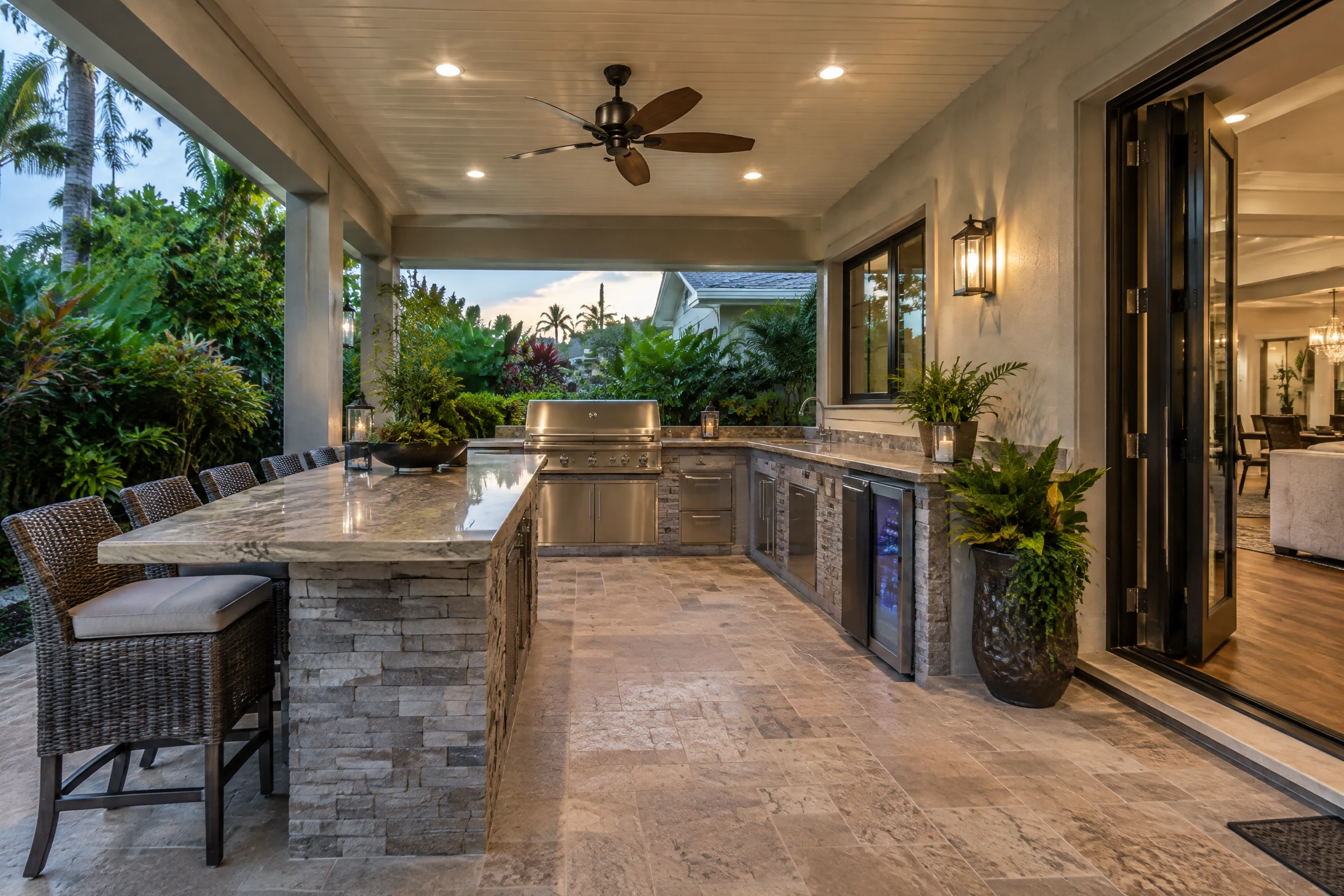 Covered lanai kitchen attached to a home with refrigerator and stone counters