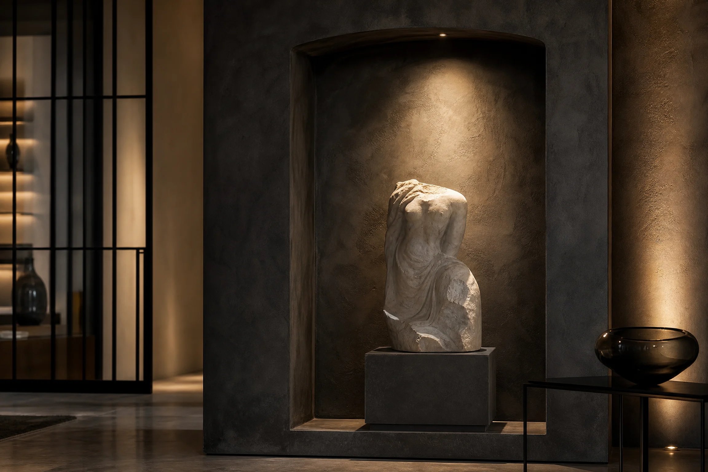 Pale marble sculpture illuminated inside a charcoal architectural niche